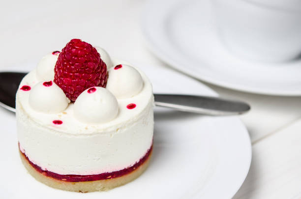 istock White airy cake with raspberry layer and raspberry berry lies on a white round plate next to a white cup, which stands on a white table 1139084250