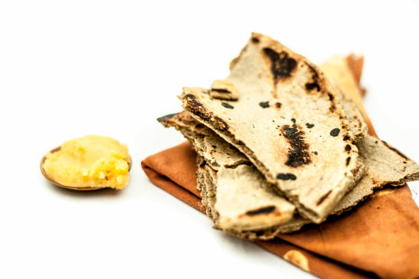 close up of common or main ingredients of malida isolated on white which are rot or bajri ki roti with jaggery in a small glass plate. - chur imagens e fotografias de stock