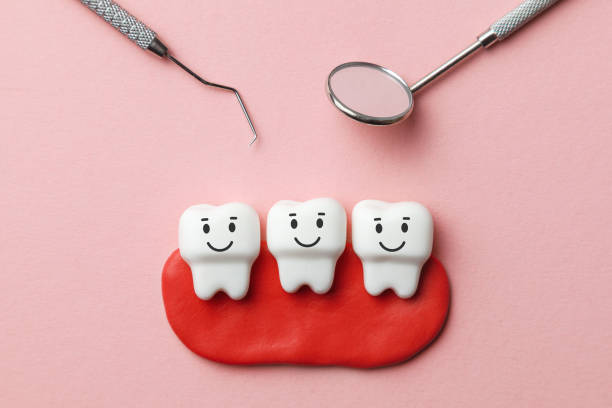 istock Healthy white teeth are smiling on pink background and dentist tools mirror, hook. 1139091855