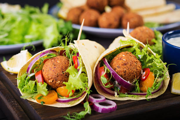 Tortilla wrap with falafel and fresh salad. Vegan tacos. Vegetarian healthy food. Tortilla wrap with falafel and fresh salad. Vegan tacos. Vegetarian healthy food. middle eastern food photos stock pictures, royalty-free photos & images