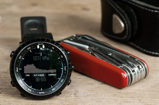 Closeup of hiking wrist watch and multipurpose knife on wooden table stock photo