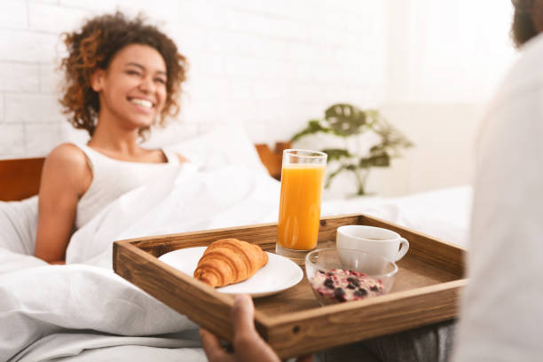 Boyfriend bring some breakfast to his girlfriend in bed Lovely boyfriend bring some breakfast to his girlfriend in morning. Romance and kindness in relationship bed breakfast pictures stock pictures, royalty-free photos & images