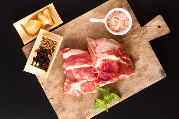 コピースペースと黒の背景にスパイスとボード上の食品コンセプトピース骨のない豚肉の襟 - chuck steak ストックフォトと画像
