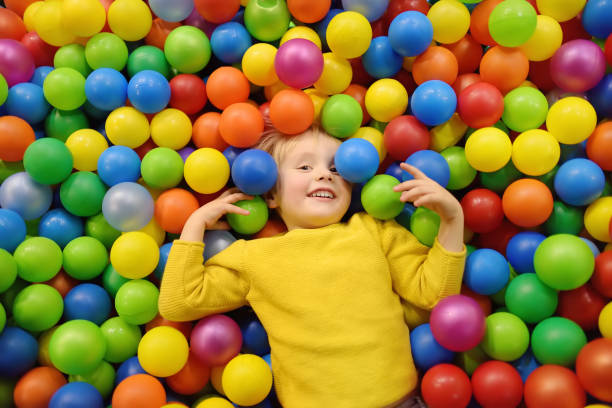 Happy little boy having fun in ball pit with colorful balls. Child playing on indoor playground. Happy little boy having fun in ball pit with colorful balls. Child playing on indoor playground. Kid jumping in ball pool. preschooler caucasian one person part of stock pictures, royalty-free photos & images