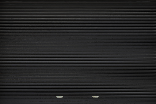 black shutter door with stainless steel holder. grunge black metal foldable door background and texture.