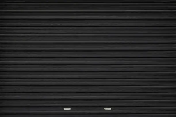 Photo of black shutter door with stainless steel holder. grunge black metal foldable door background and texture.