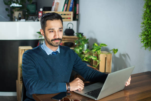 Pakistani young man working with laptop in office