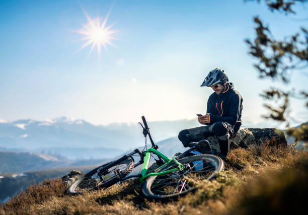 motociclista de montaña con un teléfono inteligente en la montaña - mountain biking extreme sports cycling bicycle fotografías e imágenes de stock