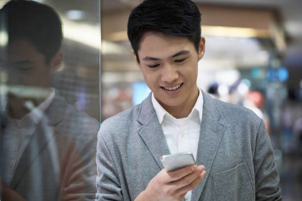 Smiling male customer using mobile phone in mall