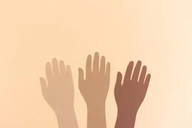 Paper cutout of hands in diversity raised up