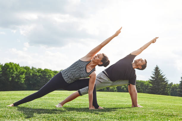 para rozciąganie. młoda para rozciąganie i wykonywanie ćwiczeń jogi w przyrodzie w słoneczny poranek. koncepcja zdrowego stylu życia - healthy lifestyle yoga vitality flexibility zdjęcia i obrazy z banku zdjęć