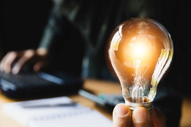istock Business man holding light bulb on the desk in office and using  computer in  financial,accounting,energy,idea concept. 1139108853