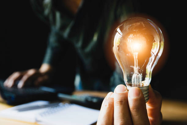 istock Business man holding light bulb on the desk in office and using  computer in  financial,accounting,energy,idea concept. 1139108860