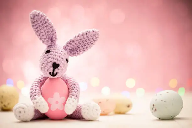 Cute homemade Easter bunny with eggs on a pastel pink background