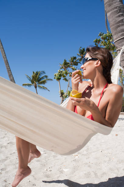 istock woman eating an orange on the beach 1139111834