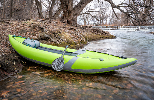 whitewater inflatable kayak on a river below diversion dam - Poudre River in Fort Collins, Colorado in early spring scenery
