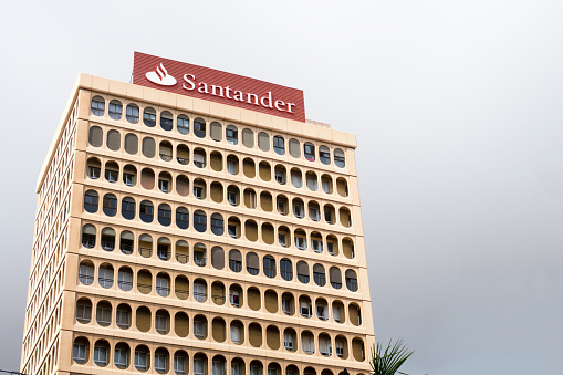 Tenerife, Spain / November 2018.  Banco Santander head office on Plaza de Candelaria against a dark clouded sky. This bank is a Spanish multinational commercial bank and financial services company founded and based in Santander, Spain. In addition to hubs in Madrid and Barcelona, Santander maintains a presence in all global financial centres as the largest Spanish banking institution in the world. Although known for its European banking operations, it has extended operations across North and South America, and more recently in continental Asia.