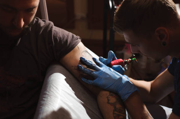 istock Tattoo artist makes a tattoo on a man's hand. 1139121123