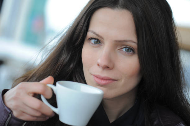 Female barista inspecting a perfect coffee in a paper cup