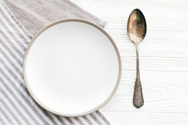 istock Diet concept. Stylish empty plate with vintage spoon on napkin on white table, flat lay. Modern set, serving for reception and party celebration. Copy space 1139127309