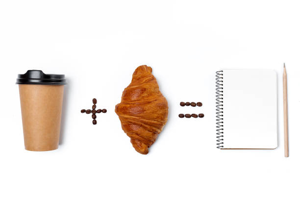 Notebook, paper coffee cup and croissant isolated on white background. Flat ley, top view. Studio light. Good morning concept.