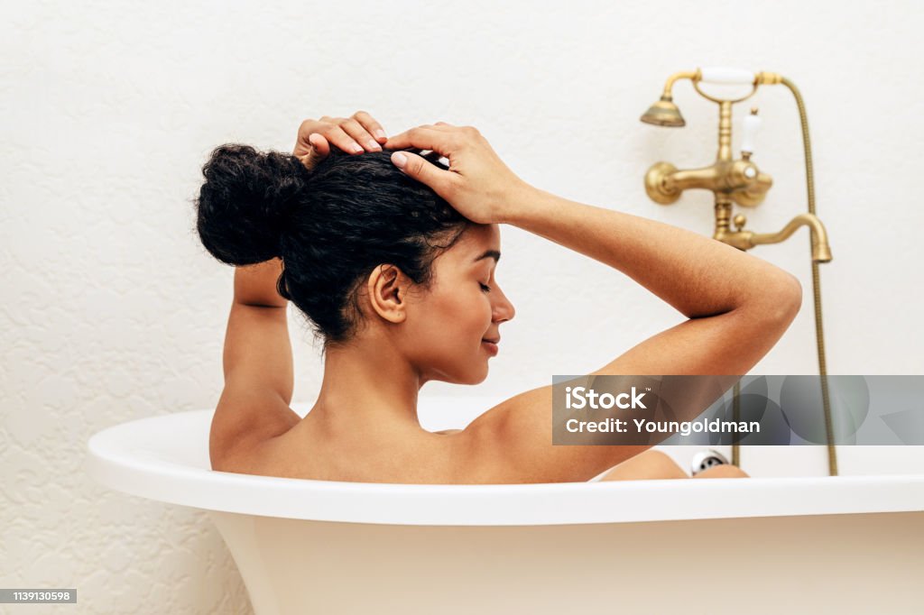 Mujer relajante en el baño, endereza su cabello - Foto de stock de Bañera libre de derechos