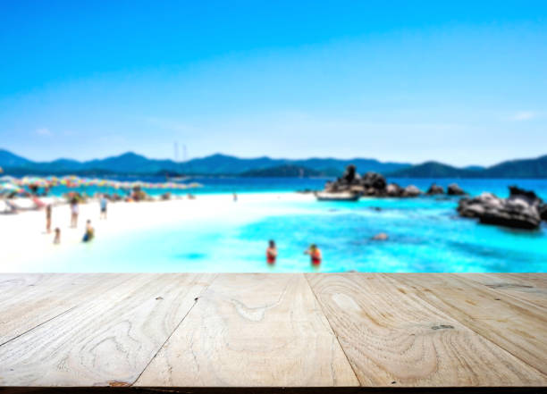 Wood table top with blurred people at the beach, summer holiday background concept - can be used for display or montage your products