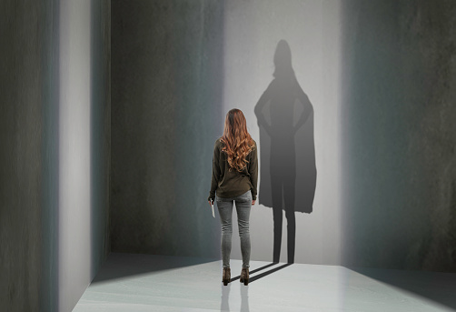 Woman standing in with superhero shadow