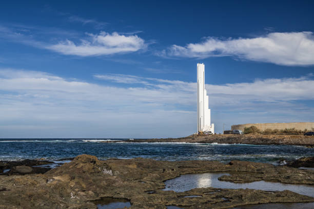 A large white modern lighthouse on the West coast of the island of Tenerife gives signals to ships in the Atlantic ocean.
