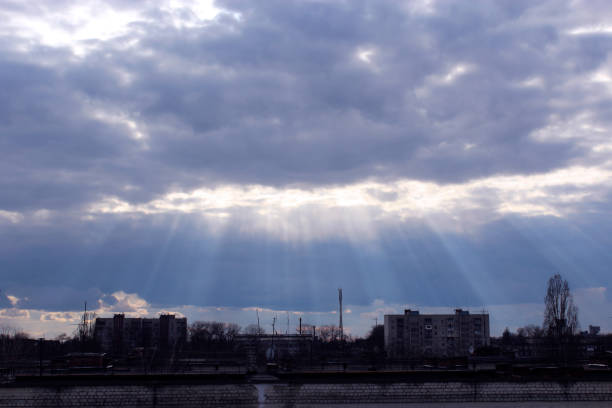 Evening landscape with sunny rays falling from clouds onto city. Beautiful sky landscape. Urban scenery with evening sun and heaven