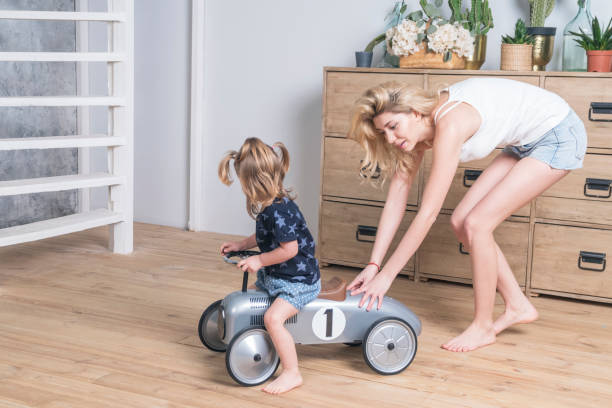 istock Mother rolls daughter on toy car 1139141654