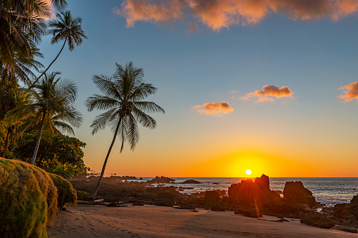Sunset along the volcanic rock beach of Corcovado national park with a sunbeam by the Pacific Ocean, Osa Peninsula, Costa Rica, Central America.