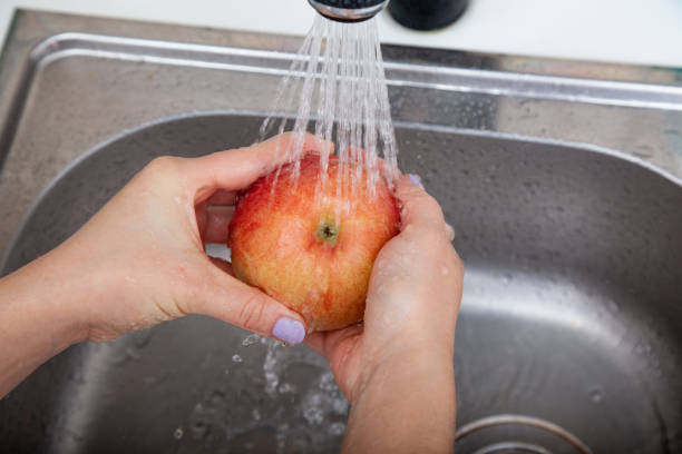 istock female hand wash up a red ripe Apple 1139145078
