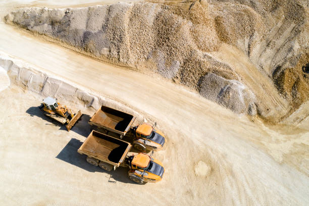 Dump Trucks and Bulldozer in a Quarry, Aerial View Aerial view of two dump trucks and a bulldozer in a quarry. sand mine stock pictures, royalty-free photos & images