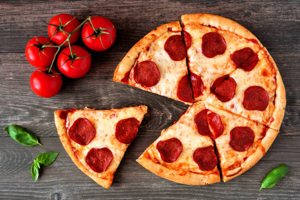 istock Pepperoni pizza with cut slices, top view table scene over wood 1139149913