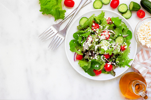 Healthy mixed salad, above scene corner border against a white marble background with copy space