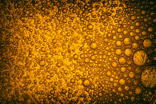 Air bubbles in gold colored liquid. Abstract texture.