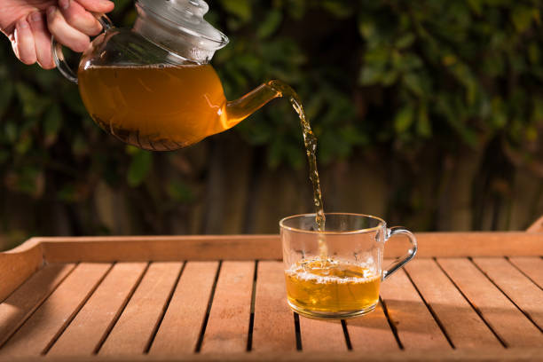 istock Pouring tea from teapot into a cup, natural background 1139157862