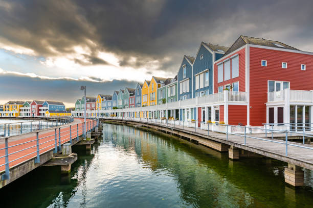 Dutch, modern, colorful vinex architecture style houses at waterside during dramatic and clouded sunset. Houten, Utrecht.