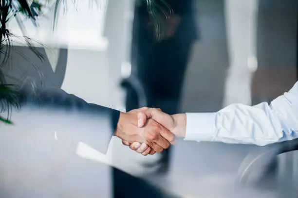 Business handshake in glass reflection in office