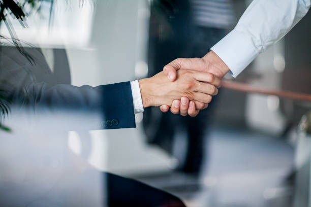 Business handshake in glass reflection in office Business handshake in glass reflection in office business handshake partnership human hand stock pictures, royalty-free photos & images