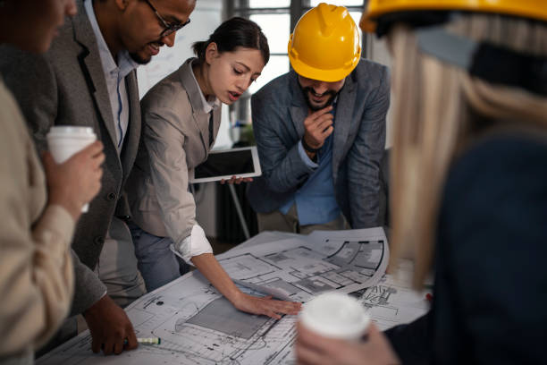 istock Group of multi ethnic architects cooperating while examining blueprints on a meeting in the office 1139176270