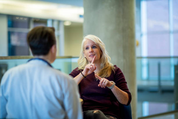 Deaf blonde woman A deaf blonde woman speaks with her partner who is a doctor. They are catching up on their lunch break. american sign language photos stock pictures, royalty-free photos & images
