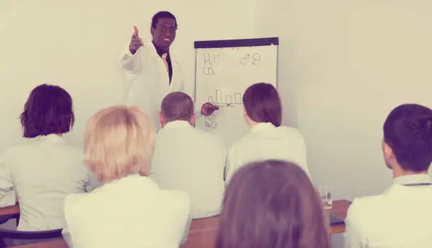 Smiling cheerful positive African American male professor giving presentation for medics in lecture hall