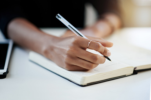 Closeup shot of a businesswoman writing in a notebook in an office