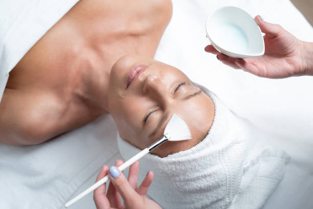 istock Beautician hands applying mask on lady forehead using cosmetic brush 1139182846