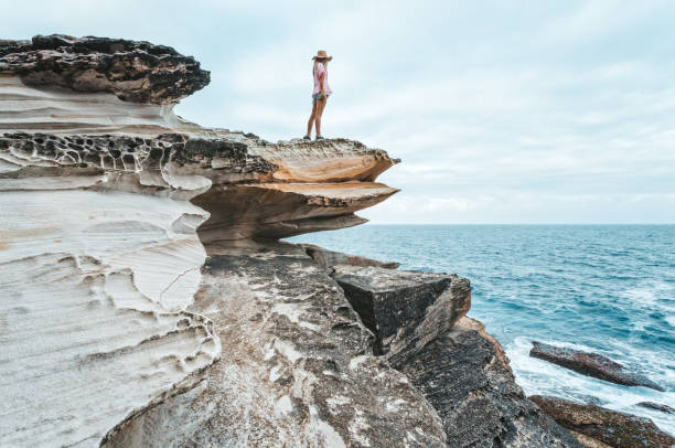 istock Woman standing on rocks on the sea coast 1139199655