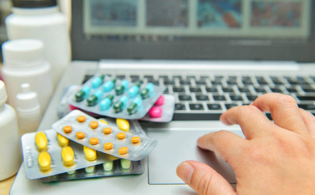 Pills, blister packs and medical bottles in front of laptop,internet shopping stock photo