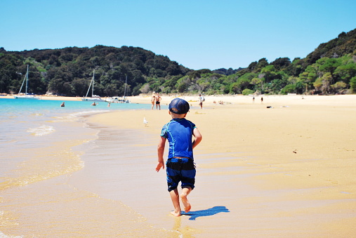 A Child Runs along the beach to the distance. This image is taken at Anchorage Beach in the Abel Tasman National Park in the Tasman District of New Zealand's South Island.