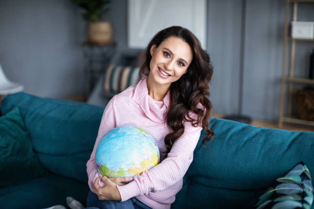 istock Smiling woman with globe at home. 1139212444
